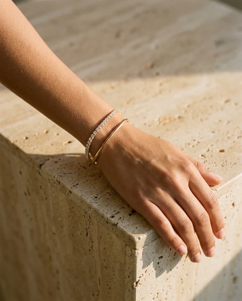 A wrist on warm travertine wearing a diamond line bracelet
